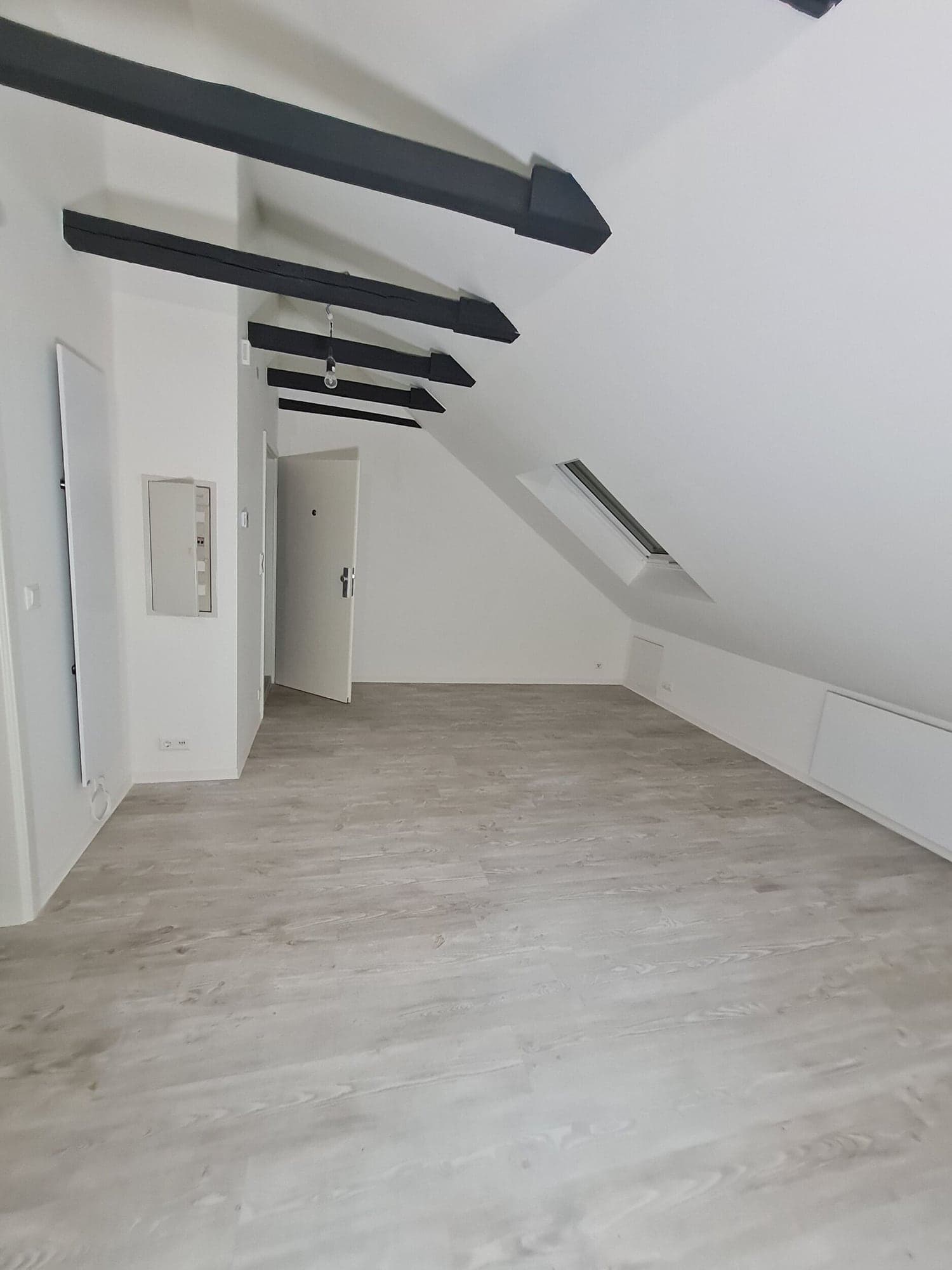 Ausgebauter Dachboden mit sichtbaren Holzbalken und Dachfenster