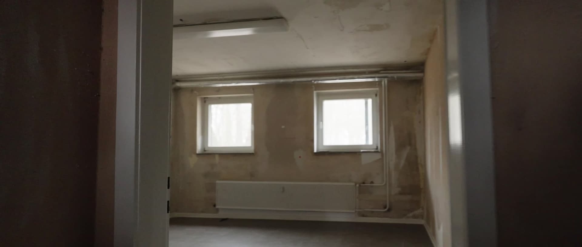 Zimmer vor der Sanierung mit fleckigen Wänden und altem Boden